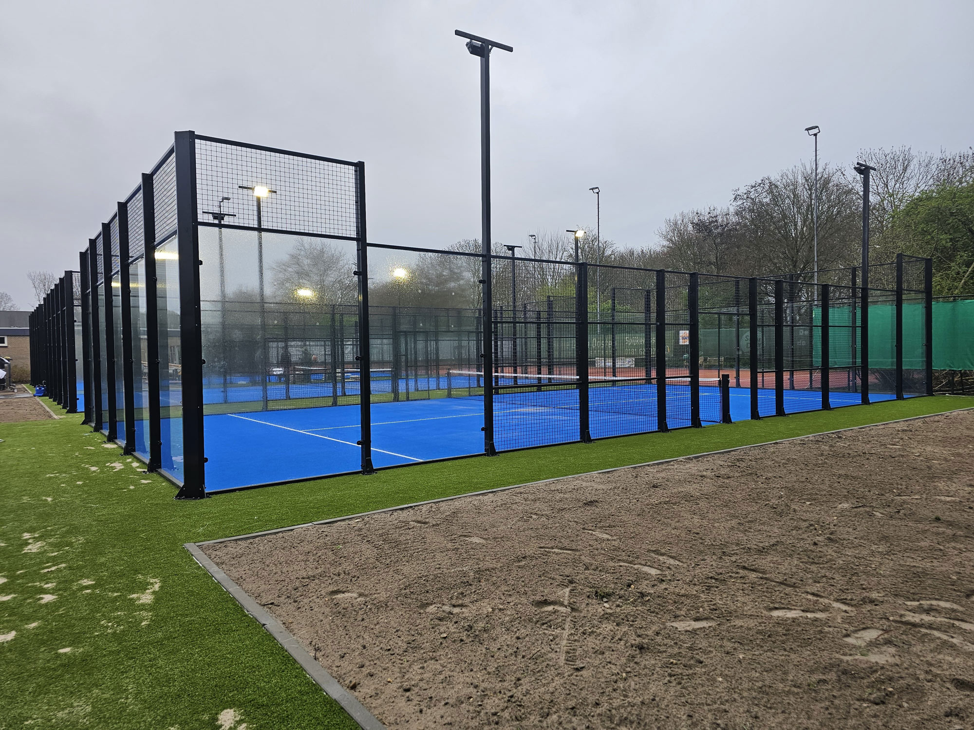 15 açık hava padel tenis kurulumu sonrası mavi zeminli çimler içerisinde bir saha